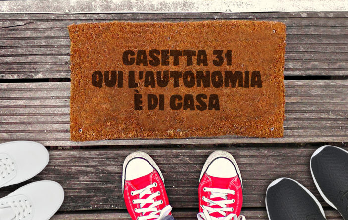 Immagine raffigurante tre paia di scarpe vicino lo zerbino della casetta, con su scritto: "Casetta 31. Qui l'autonomia è di casa".